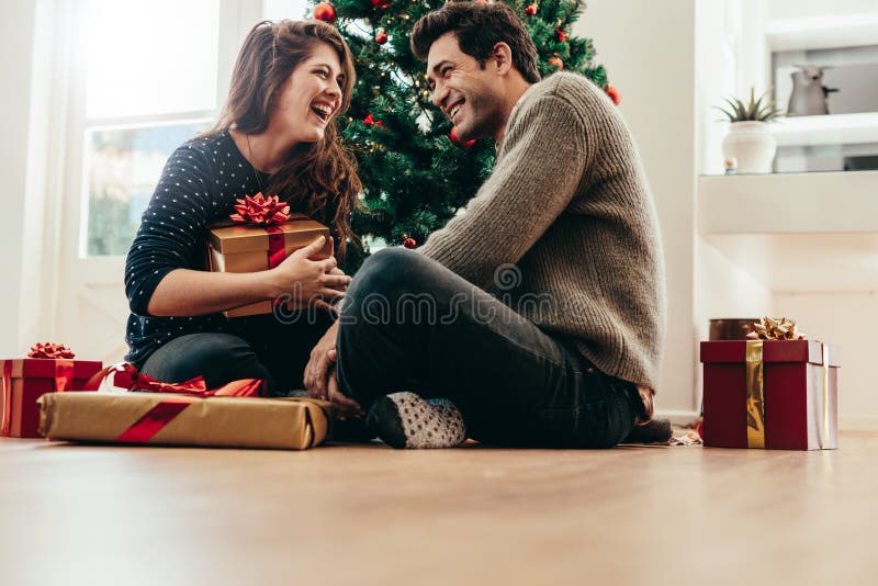 Jong paar die Kerstmisgiften thuis ruilen stock foto Jong paar die Kerstmisgiften thuis ruilen stock foto