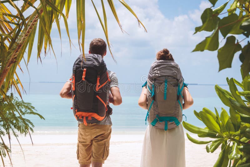 Jong paar die met grote rugzak aan het strand in een tropische vakantiebestemming lopen stock fotografie Jong paar die met grote rugzak aan het strand in een tropische vakantiebestemming lopen stock fotografie