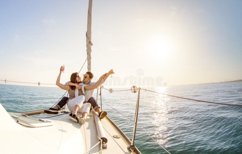 Jong paar in liefde op zeilboot met champagne bij zonsondergang - Hap