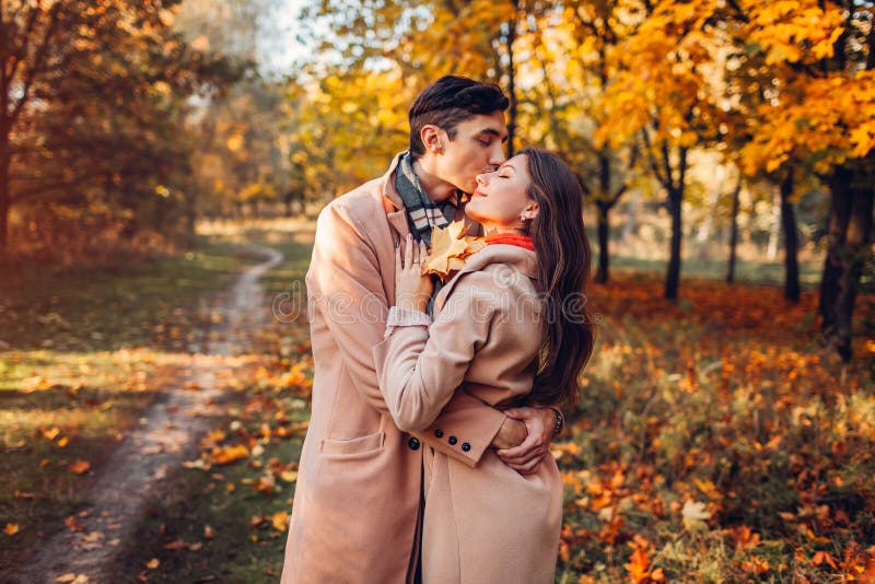 Jong paar in liefdegangen in de herfstbos onder kleurrijke bomen En mensen die koesteren kussen stock fotografie Jong paar in liefdegangen in de herfstbos onder kleurrijke bomen En mensen die koesteren kussen stock fotografie