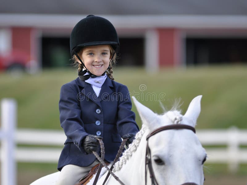 Small young caucasian girl in an equestrian outfit sitting on a white horse. Small young caucasian girl in an equestrian outfit sitting on a white horse.