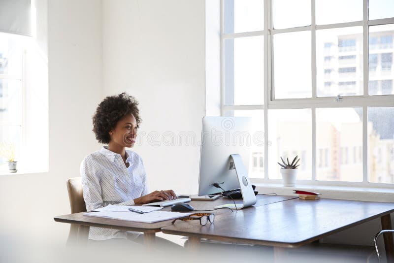 Jong zwarte die bij computer in een bureau werken stock foto Jong zwarte die bij computer in een bureau werken stock foto
