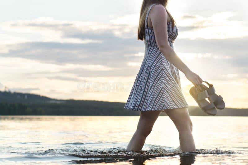 Jonge aantrekkelijke vrouw die in meerwater bij zonsondergang lopen royalty-vrije stock afbeelding Jonge aantrekkelijke vrouw die in meerwater bij zonsondergang lopen royalty-vrije stock afbeelding