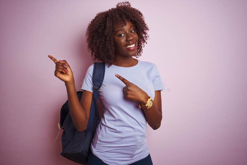 Young african afro tourist woman wearing backpack standing over isolated pink background smiling and looking at the camera pointing with two hands and fingers to the side. Young african afro tourist woman wearing backpack standing over isolated pink background smiling and looking at the camera pointing with two hands and fingers to the side