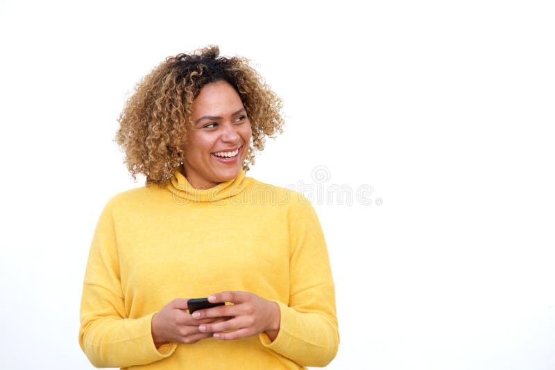 Portrait of young african american woman holding cellphone and looking away by white background. Portrait of young african american woman holding cellphone and looking away by white background