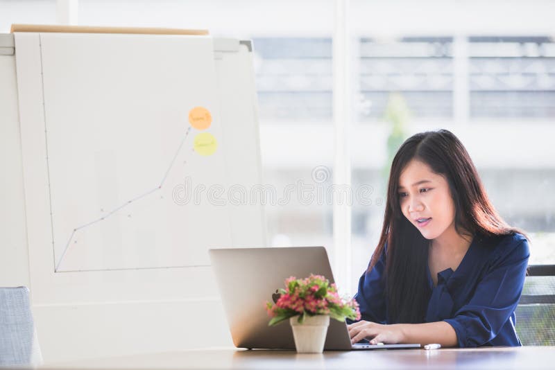 Jonge Aziatische bedrijfsdievrouw het werken aan laptop wordt geconcentreerd aan lusje stock afbeelding Jonge Aziatische bedrijfsdievrouw het werken aan laptop wordt geconcentreerd aan lusje stock afbeelding