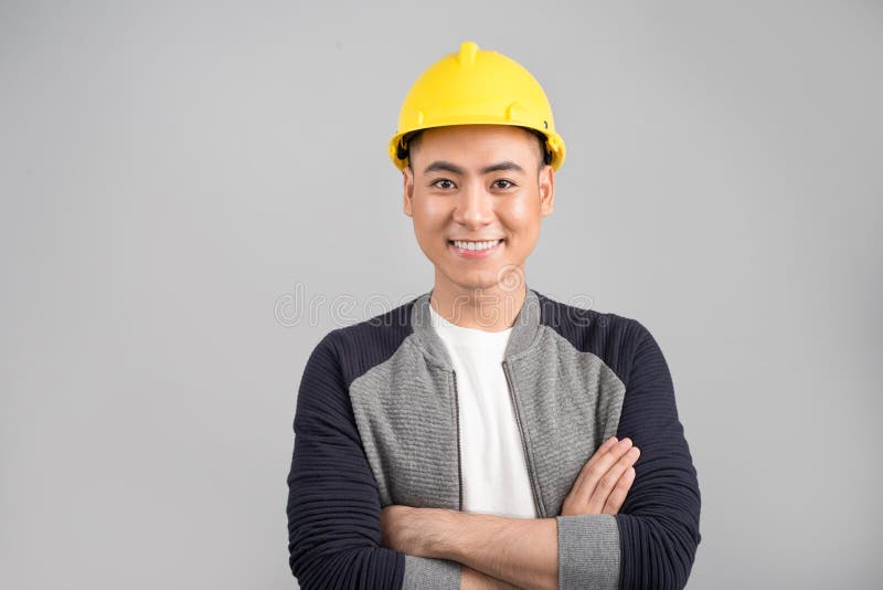 Jonge Aziatische mens die met bouwhelm aan camera kijken stock afbeeldingen Jonge Aziatische mens die met bouwhelm aan camera kijken stock afbeeldingen