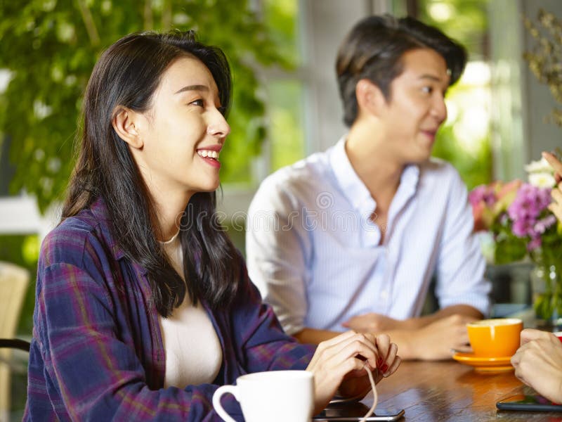 Jonge Aziatische volwassenen die aan vrienden in koffiewinkel spreken royalty-vrije stock afbeelding Jonge Aziatische volwassenen die aan vrienden in koffiewinkel spreken royalty-vrije stock afbeelding