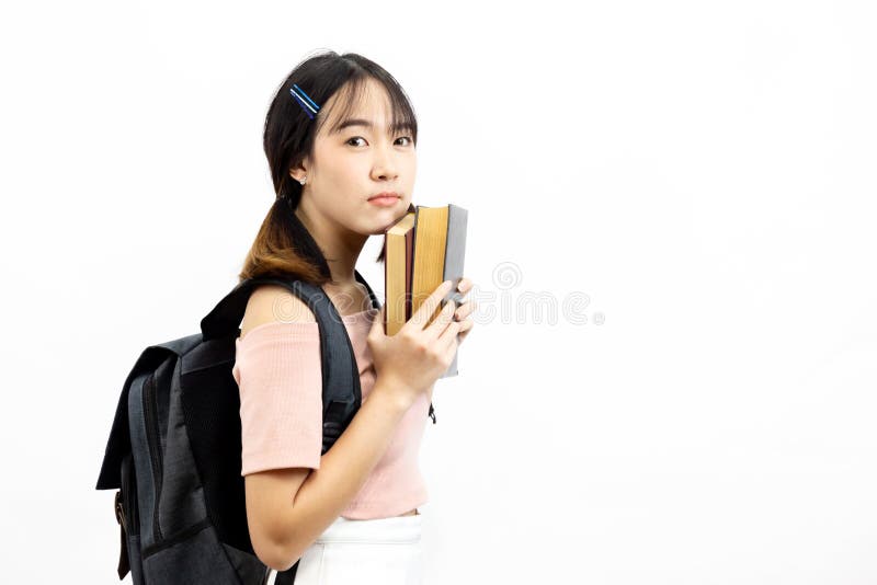 Jonge Aziatische vrouwelijke studenten die die stapel van boeken met zak houden over witte achtergrond wordt geïsoleerd royalty-vrije stock fotografie Jonge Aziatische vrouwelijke studenten die die stapel van boeken met zak houden over witte achtergrond wordt geïsoleerd royalty-vrije stock fotografie
