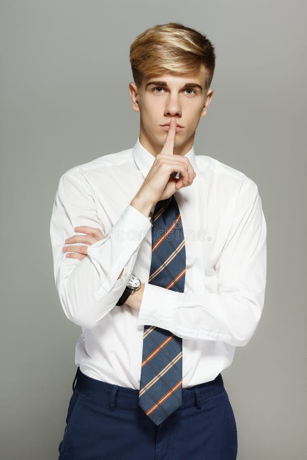 Business man with finger on lips asking for silence over white background. Business man with finger on lips asking for silence over white background