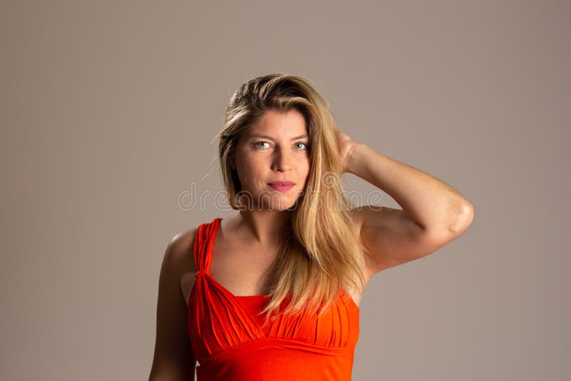 Portrait of young blonde woman smiling with raised arm and hand in hair. Brazilian in neutral background. Empowered and happy. Portrait of young blonde woman smiling with raised arm and hand in hair. Brazilian in neutral background. Empowered and happy