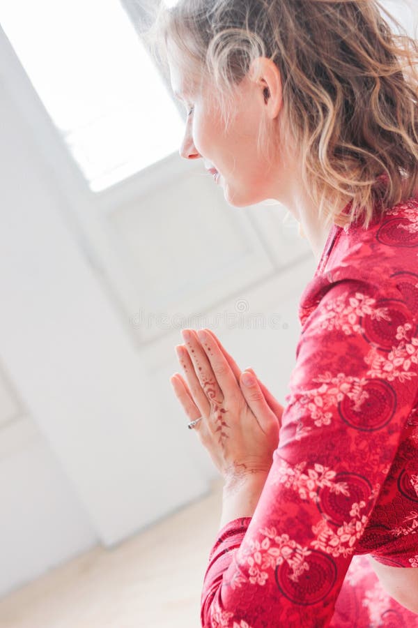 Jonge blondevrouw in rode etnische kostuum het praktizeren yogaasana Namaste in lichte studio stock afbeeldingen Jonge blondevrouw in rode etnische kostuum het praktizeren yogaasana Namaste in lichte studio stock afbeeldingen