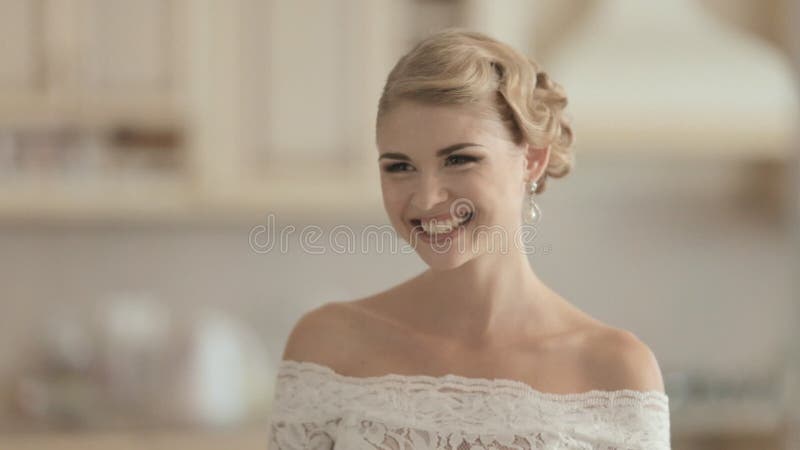 Jonge bruid in een kleding die van het kanthuwelijk lachen bij