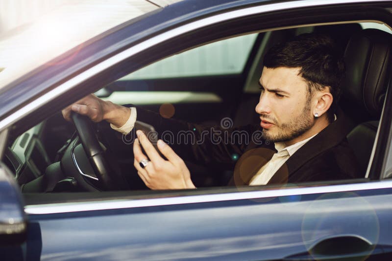 Jonge bussinesman in kostuum spreekt telefonisch in zijn auto De zaken zien eruit Testaandrijving van de nieuwe auto royalty-vrije stock fotografie Jonge bussinesman in kostuum spreekt telefonisch in zijn auto De zaken zien eruit Testaandrijving van de nieuwe auto royalty-vrije stock fotografie