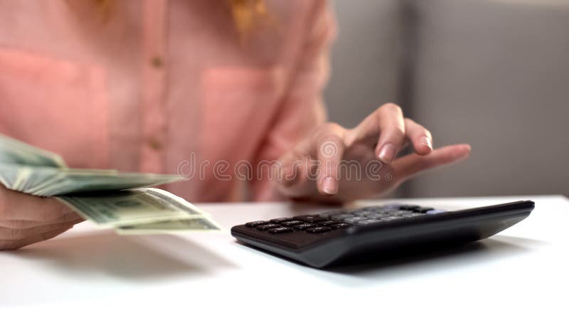 Jonge dame tellende uitgaven die calculator gebruiken, die dollars in hand houden, inkomen stock afbeeldingen Jonge dame tellende uitgaven die calculator gebruiken, die dollars in hand houden, inkomen stock afbeeldingen