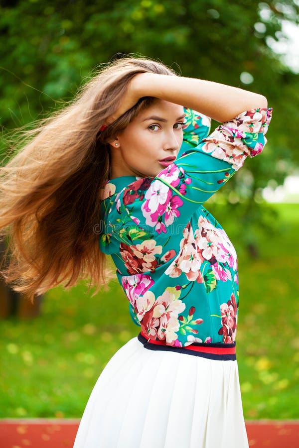 Young happy brunette woman in flowers blouse in the summer park. Young happy brunette woman in flowers blouse in the summer park