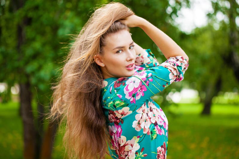 Young happy brunette woman in flowers blouse in the summer park. Young happy brunette woman in flowers blouse in the summer park