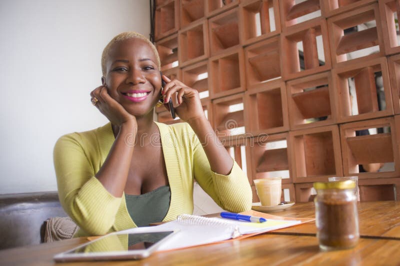 Jonge elegante en mooie zwarte Afrikaanse Amerikaanse bedrijfsvrouw die online met mobiele telefoon bij koffiewinkel gelukkig gli stock afbeelding Jonge elegante en mooie zwarte Afrikaanse Amerikaanse bedrijfsvrouw die online met mobiele telefoon bij koffiewinkel gelukkig gli stock afbeelding