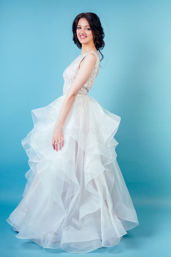 Jonge en mooie vrouw met make-up in lange witte bruidsjurk in studio op een blauwe achtergrond begrip royalty-vrije stock foto Jonge en mooie vrouw met make-up in lange witte bruidsjurk in studio op een blauwe achtergrond begrip royalty-vrije stock foto