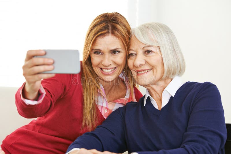 Young and old women taking selfie together with a smartphone. Young and old women taking selfie together with a smartphone