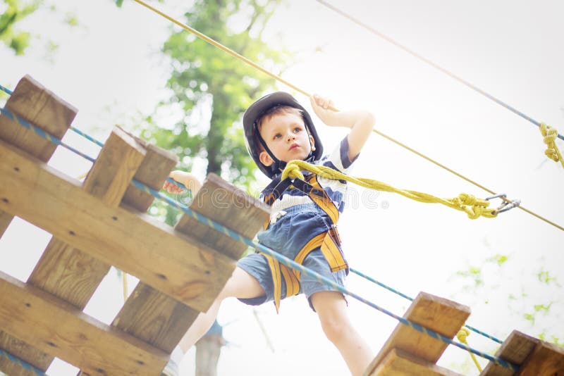 Jonge geitjes die in avonturenpark beklimmen De jongen geniet van beklimmend in de kabel stock fotografie Jonge geitjes die in avonturenpark beklimmen De jongen geniet van beklimmend in de kabel stock fotografie