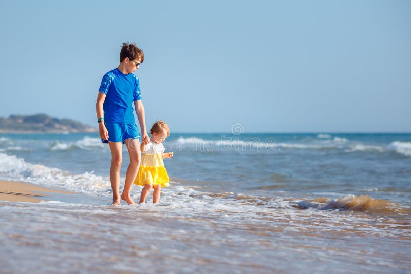 Jonge geitjes die op tropisch strand spelen Grote broer samen met zijn kleine zuster op zee kust bij zonsondergang De vakantie va stock fotografie Jonge geitjes die op tropisch strand spelen Grote broer samen met zijn kleine zuster op zee kust bij zonsondergang De vakantie va stock fotografie