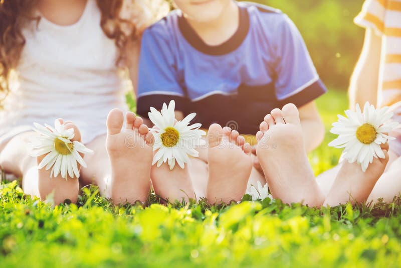 Jonge geitjesvoeten met madeliefjebloem op groen gras in een de zomerpark royalty-vrije stock afbeelding Jonge geitjesvoeten met madeliefjebloem op groen gras in een de zomerpark royalty-vrije stock afbeelding