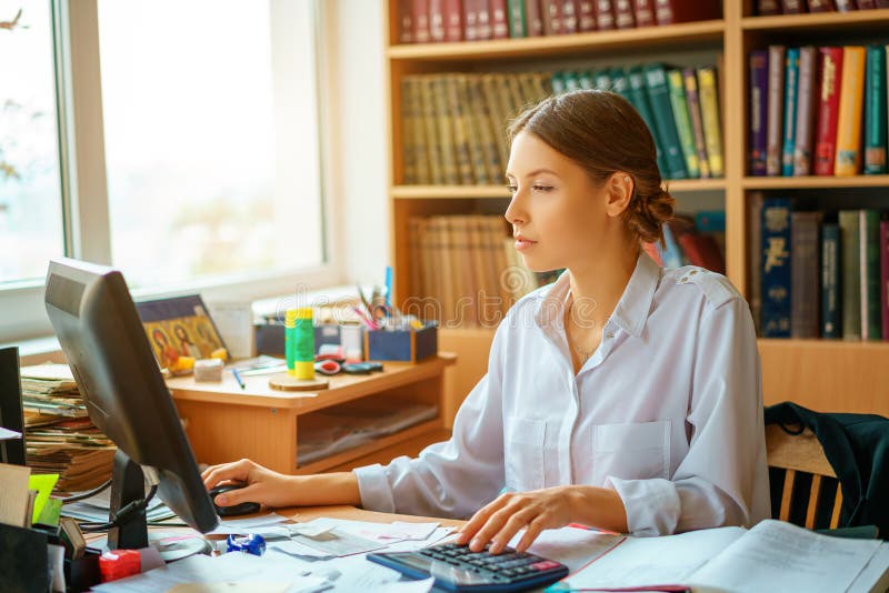 Jonge gelukkige bedrijfsdame in witte overhemdszitting bij lijst met computer en documenten werkomgeving royalty-vrije stock fotografie Jonge gelukkige bedrijfsdame in witte overhemdszitting bij lijst met computer en documenten werkomgeving royalty-vrije stock fotografie