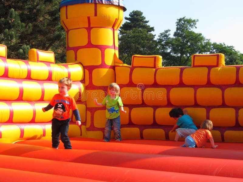 Jonge gelukkige kinderen die op een bouncykasteel spelen. stock afbeeldingen Jonge gelukkige kinderen die op een bouncykasteel spelen. stock afbeeldingen