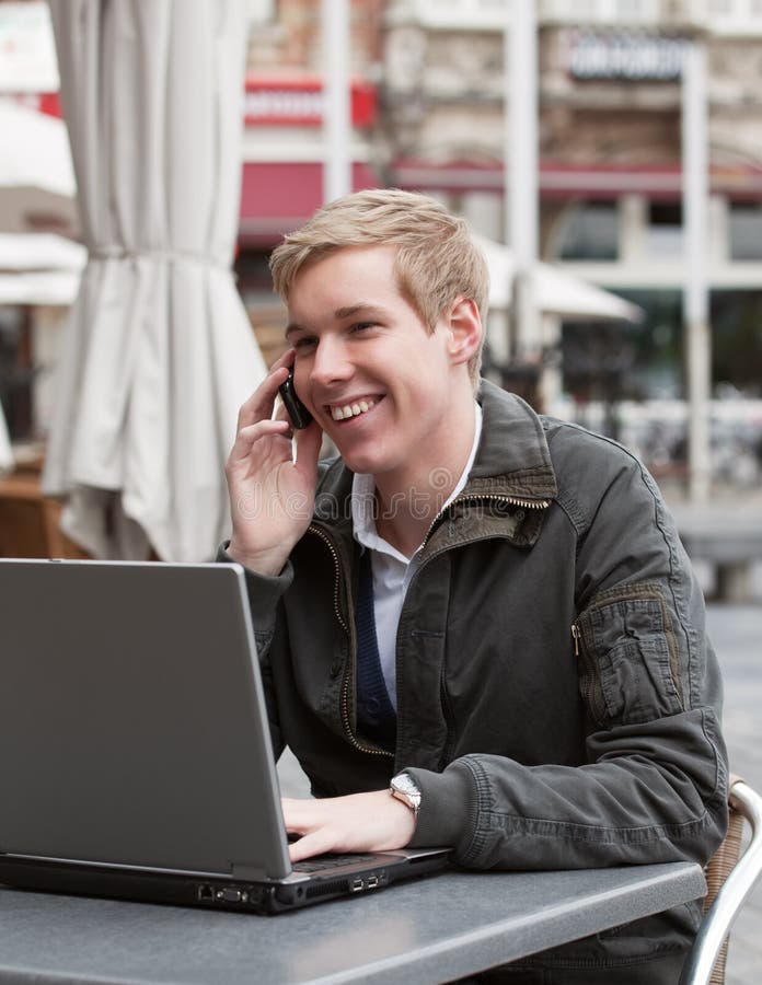 Jonge gelukkige mens met telefoon en laptop royalty-vrije stock afbeeldingen Jonge gelukkige mens met telefoon en laptop royalty-vrije stock afbeeldingen