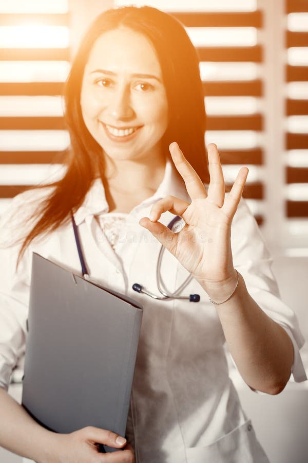 Jonge gelukkige vrolijke arts in het witte eenvormige o.k. gesturing stock foto Jonge gelukkige vrolijke arts in het witte eenvormige o.k. gesturing stock foto