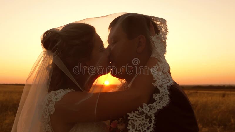 Jonge getrouwde stellen zoenen en knuffelen in zonsondergang Gehuwd leven man en vrouw