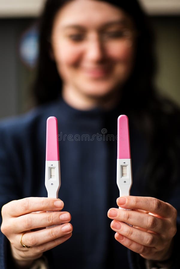 Jonge glimlachende vrouw met de tests van de huiszwangerschap royalty-vrije stock foto Jonge glimlachende vrouw met de tests van de huiszwangerschap royalty-vrije stock foto