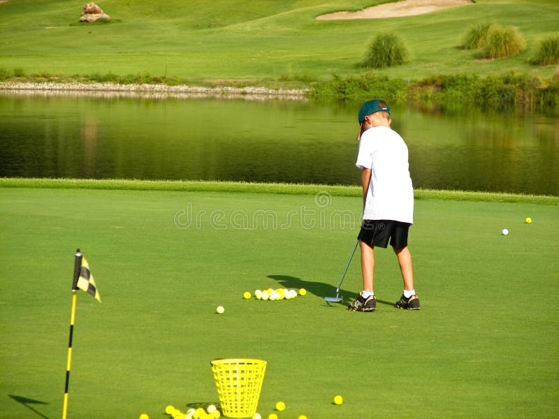 Young boy putting on the green of a golf course. Young boy putting on the green of a golf course.