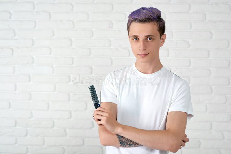 Jonge herenkapper die met gestemd haar camera bekijken die zich op witte bakstenen muur bevinden stock afbeelding Jonge herenkapper die met gestemd haar camera bekijken die zich op witte bakstenen muur bevinden stock afbeelding