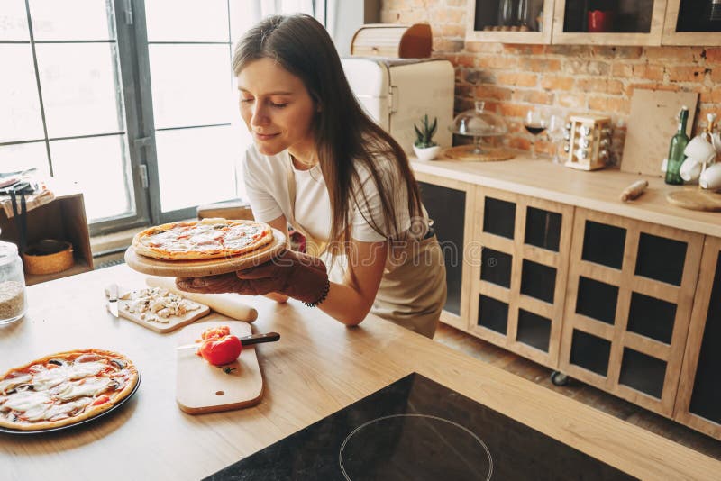 Jonge het bakselpizza van de vrouwenhuisvrouw voor haar familie stock fotografie Jonge het bakselpizza van de vrouwenhuisvrouw voor haar familie stock fotografie