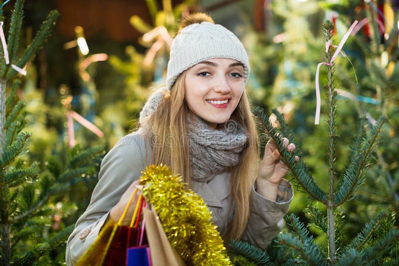 Jonge het glimlachen vrouw het kopen Kerstmisboom bij feestelijke markt stock afbeeldingen Jonge het glimlachen vrouw het kopen Kerstmisboom bij feestelijke markt stock afbeeldingen