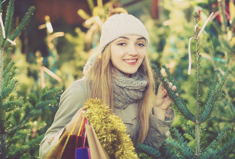 Jonge het glimlachen vrouw het kopen Kerstmisboom bij feestelijke markt stock foto's Jonge het glimlachen vrouw het kopen Kerstmisboom bij feestelijke markt stock foto's