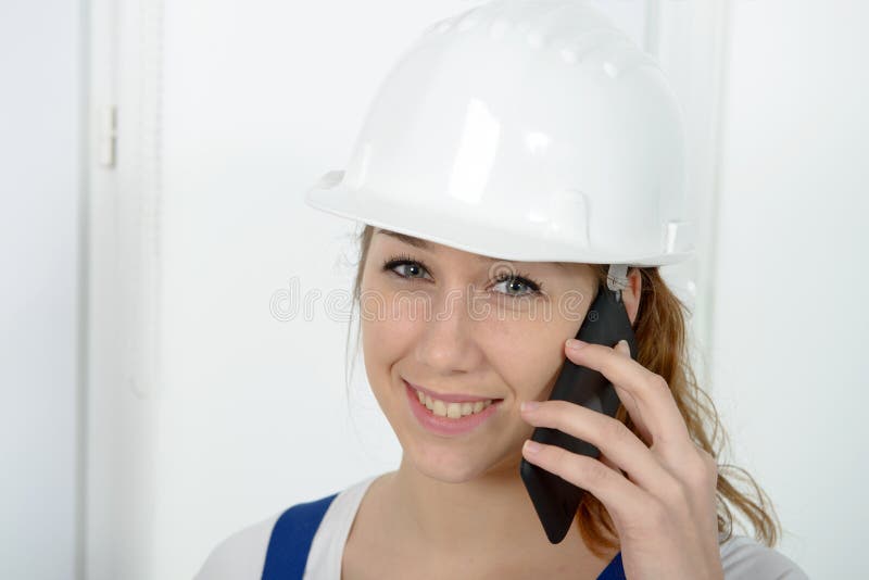 Jonge ingenieursvrouw die met veiligheidsbouwvakker op telefoon spreken royalty-vrije stock afbeeldingen Jonge ingenieursvrouw die met veiligheidsbouwvakker op telefoon spreken royalty-vrije stock afbeeldingen