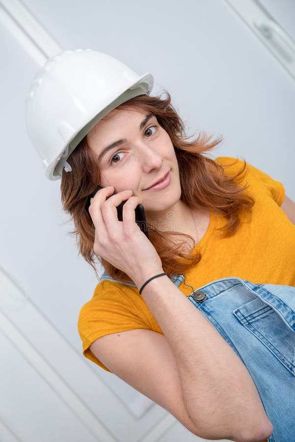 Jonge ingenieursvrouw die met veiligheidsbouwvakker op telefoon spreken stock afbeeldingen Jonge ingenieursvrouw die met veiligheidsbouwvakker op telefoon spreken stock afbeeldingen