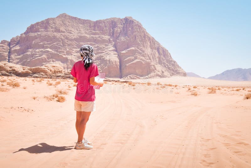 Young caucasian woman hold map disoriented lost read map alone in desert in extreme heat. Wadi rum desert hike and hiking routes. Young caucasian woman hold map disoriented lost read map alone in desert in extreme heat. Wadi rum desert hike and hiking routes.