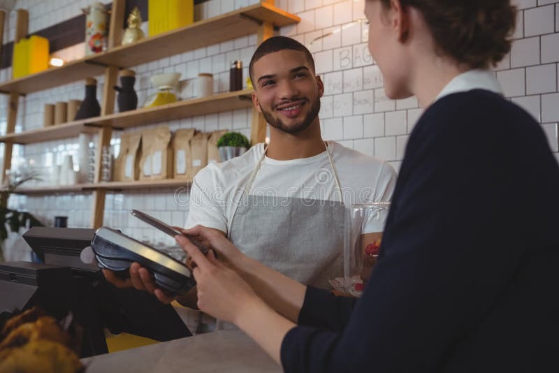 Jonge kelner die creditcardlezer tonen aan eigenaar in koffie royalty-vrije stock fotografie Jonge kelner die creditcardlezer tonen aan eigenaar in koffie royalty-vrije stock fotografie