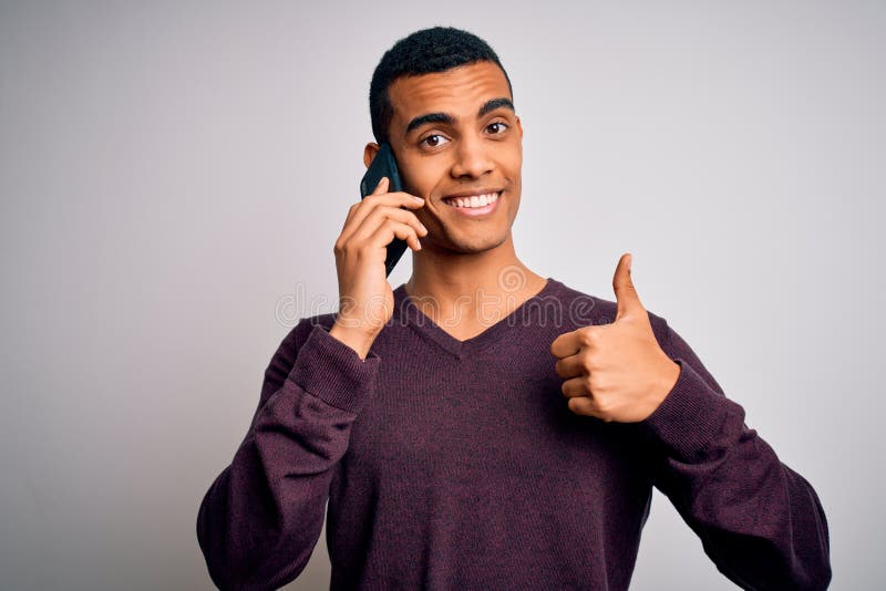 Young handsome african american man having conversation talking on the smartphone happy with big smile doing ok sign, thumb up with fingers, excellent sign. Young handsome african american man having conversation talking on the smartphone happy with big smile doing ok sign, thumb up with fingers, excellent sign