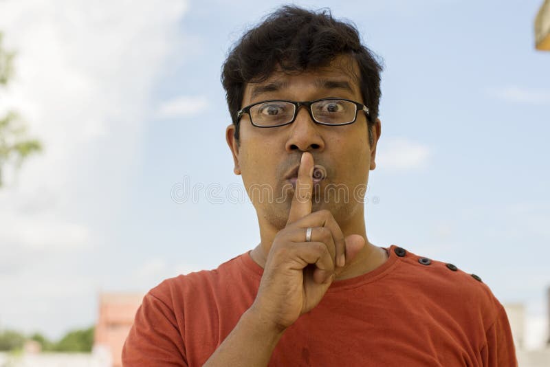 Young handsome man holding index finger on lips asking for silence. A middle aged man keeps finger on lips, asks not tell secret information or keep silence. Secret concept. Young handsome man holding index finger on lips asking for silence. A middle aged man keeps finger on lips, asks not tell secret information or keep silence. Secret concept