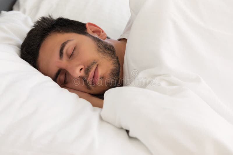 Jonge knappe mensenslaap in zijn bed stock afbeelding Jonge knappe mensenslaap in zijn bed stock afbeelding