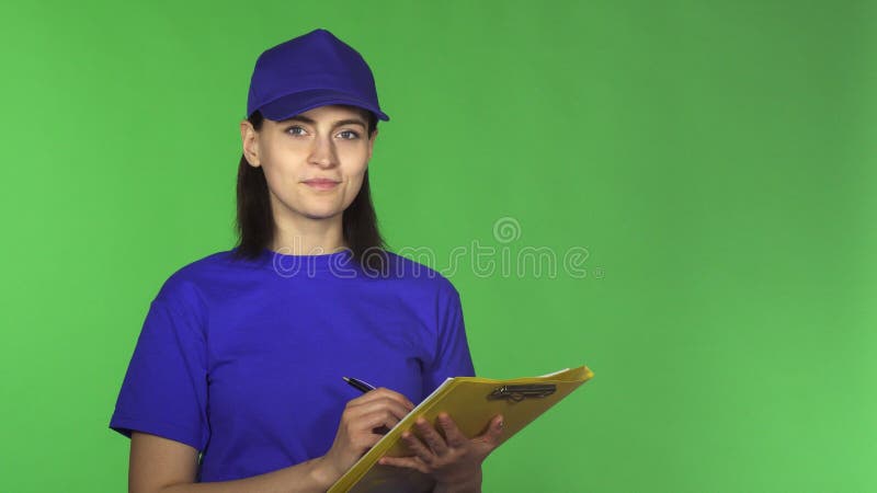 Jonge leveringsvrouw die documenten controleren op een klembord die aan de camera glimlachen stock afbeelding Jonge leveringsvrouw die documenten controleren op een klembord die aan de camera glimlachen stock afbeelding
