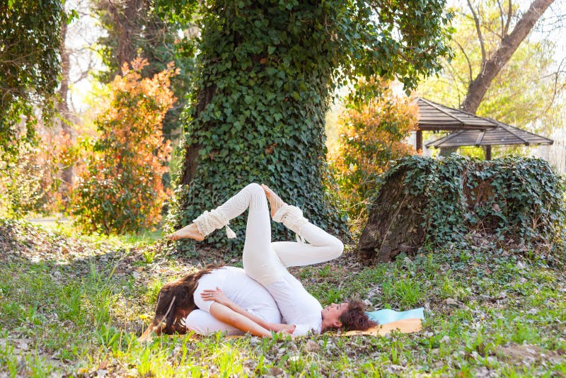 Jonge man en vrouwen de yoga van de praktijkpartner openlucht in houten de zomerdag stock fotografie Jonge man en vrouwen de yoga van de praktijkpartner openlucht in houten de zomerdag stock fotografie