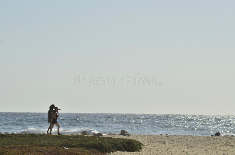 Jonge man en vrouwen het paar silhouetteert het lopen Vreedzaam strand Baja, Mexico stock foto's Jonge man en vrouwen het paar silhouetteert het lopen Vreedzaam strand Baja, Mexico stock foto's