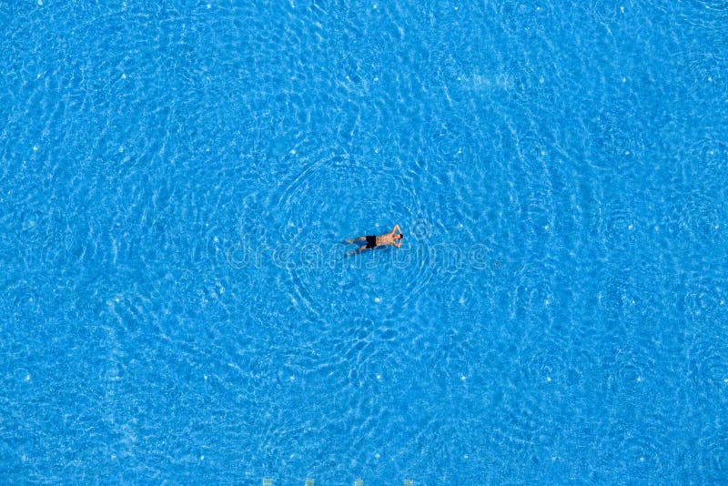 Jonge man zwemt in het zwembad in het hotel Weergeven vanaf boven