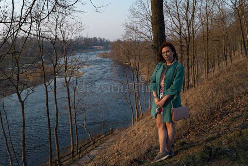 Jonge maniervrouw die en van zonsondergang ontspannen genieten dichtbij een rivier in Bauska, Letland, 2019 stock afbeelding Jonge maniervrouw die en van zonsondergang ontspannen genieten dichtbij een rivier in Bauska, Letland, 2019 stock afbeelding